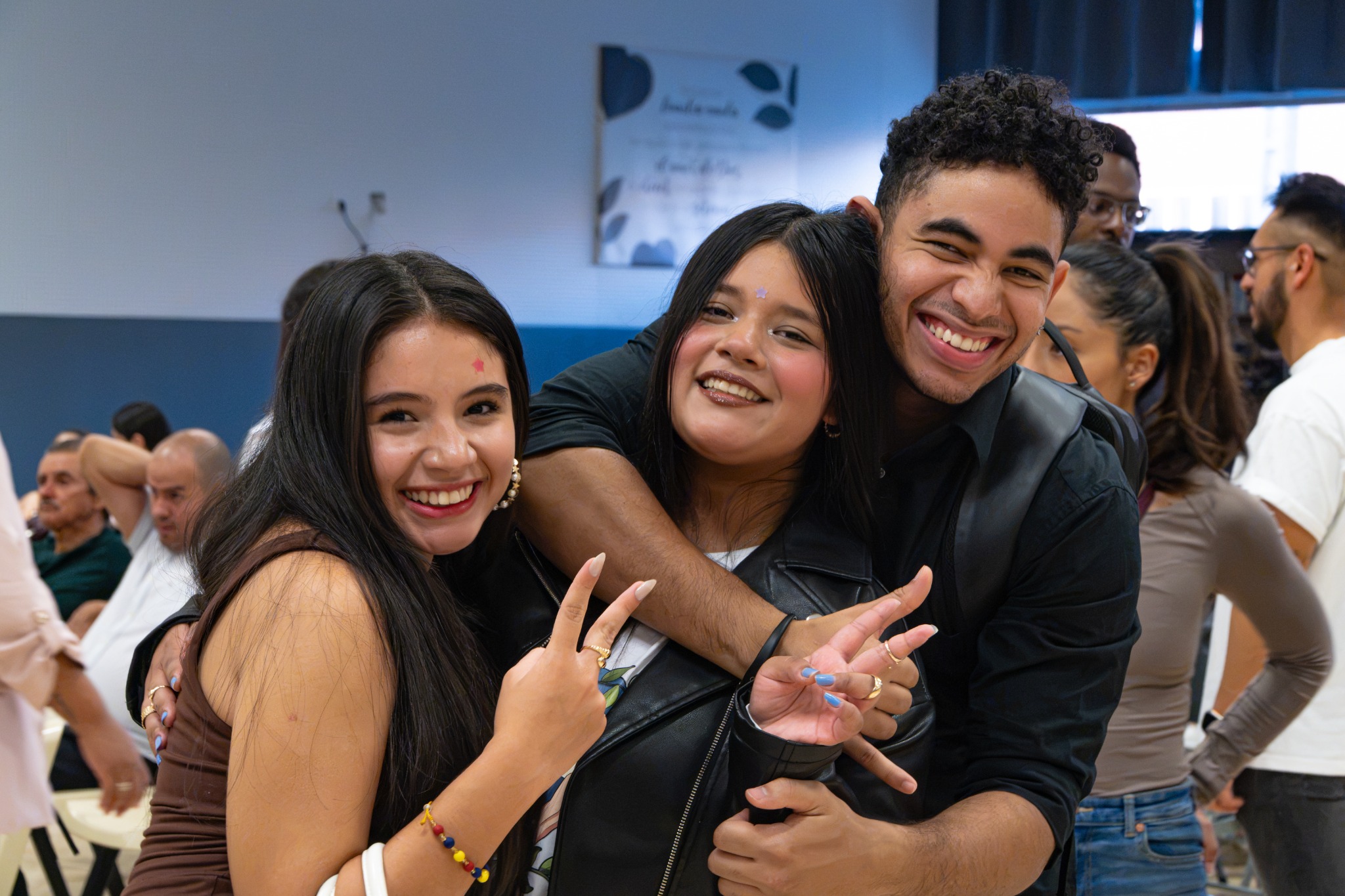 Tres jóvenes sonríen juntos durante un encuentro de la iglesia